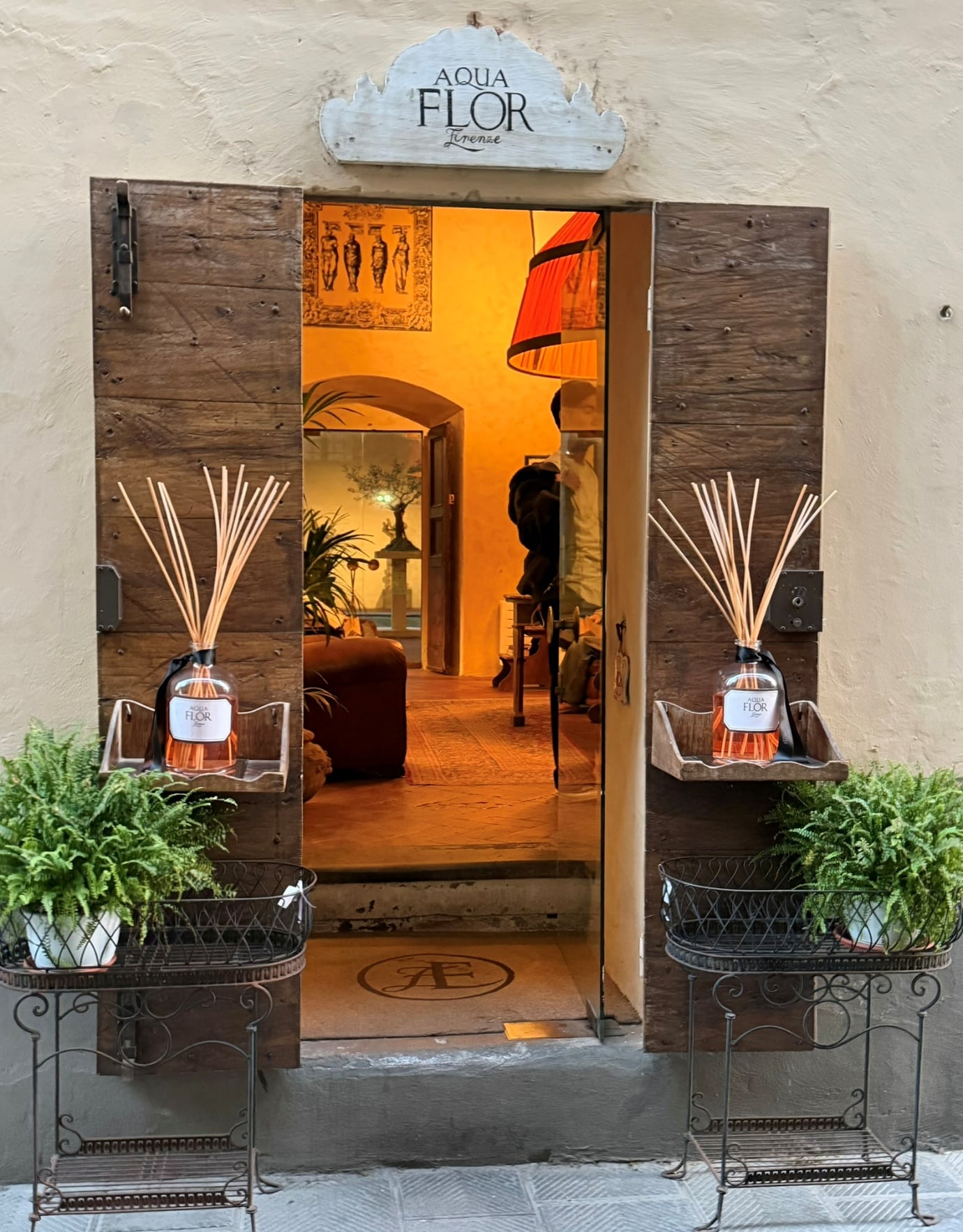 The entrance to Aquaflor perfumery, with reed diffusers and ferns beside the wooden doors