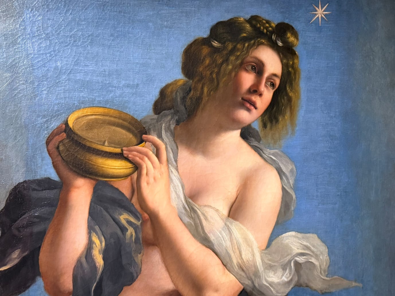 A Baroque painting of a woman holding a lit oil lamp and looking toward a star