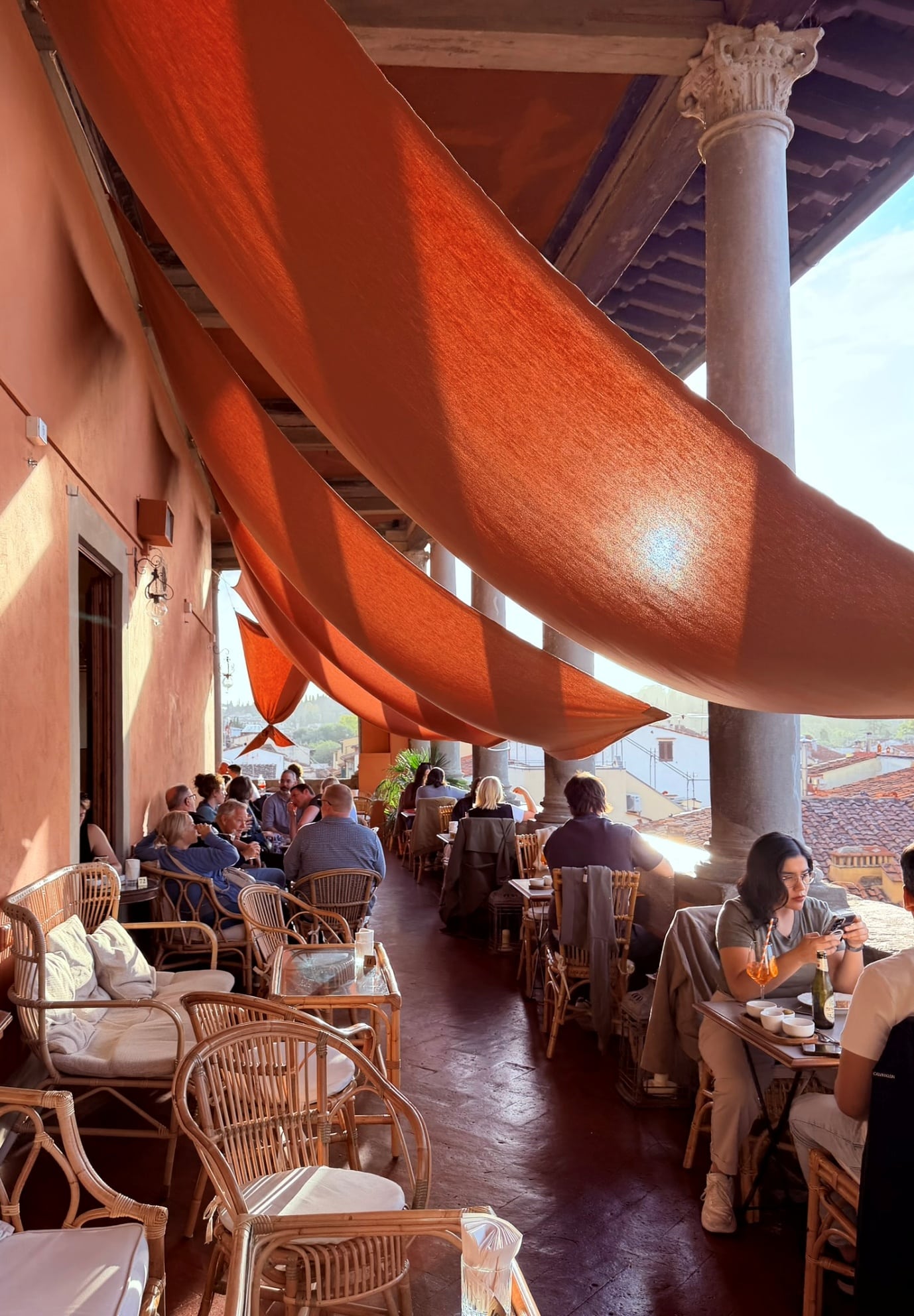 Tables under orange awnings on the loggia of Palazzo Guadagni, looking over Florence's rooftops