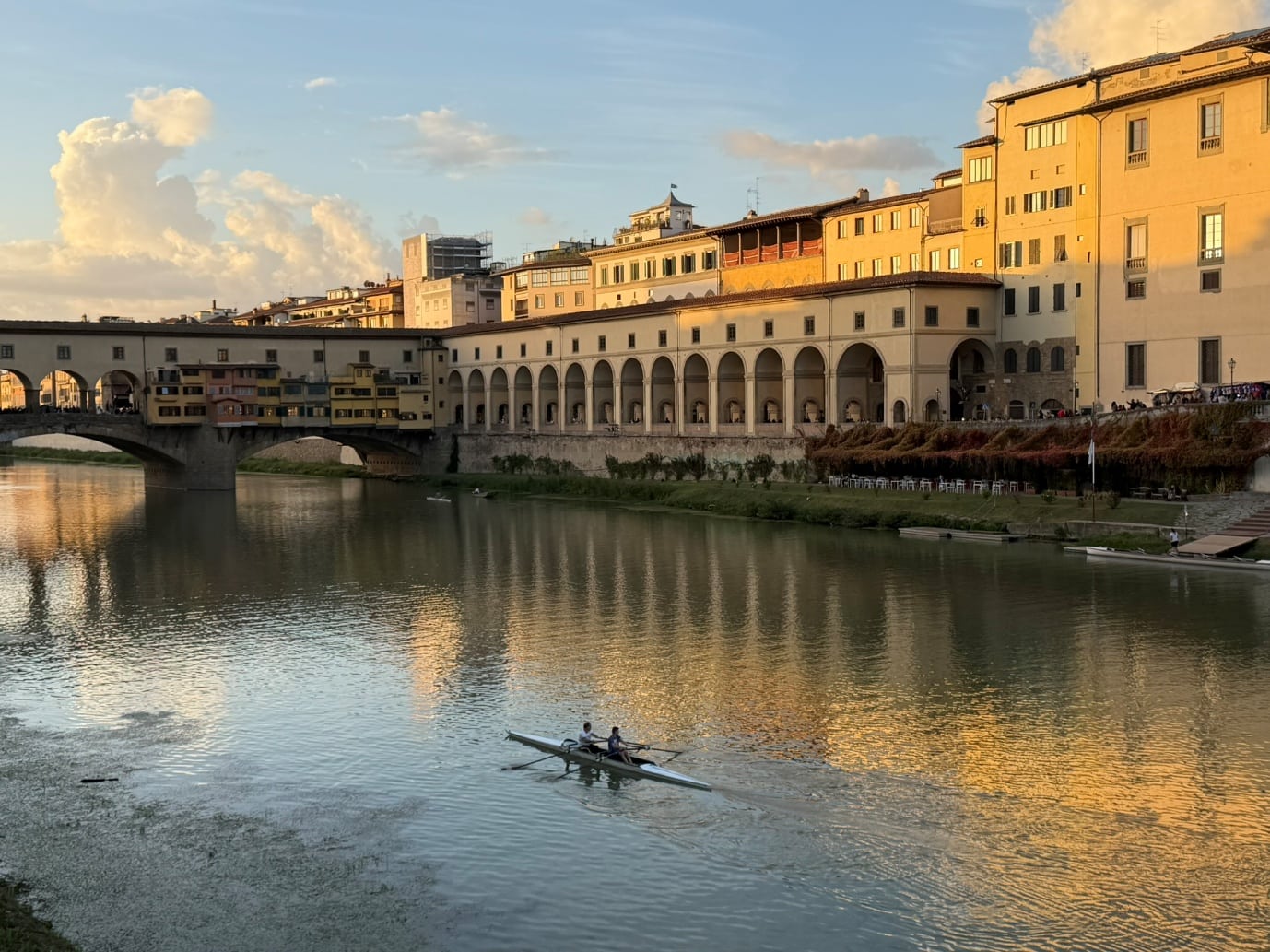Two people rowing on the Arno beside the Ponte Vecchio