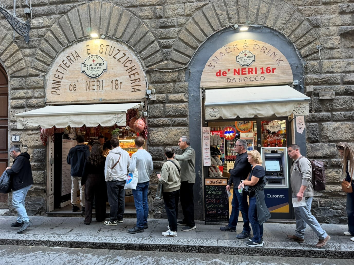 A queue outside Schiacciateria de' Neri on a stone street in Florence