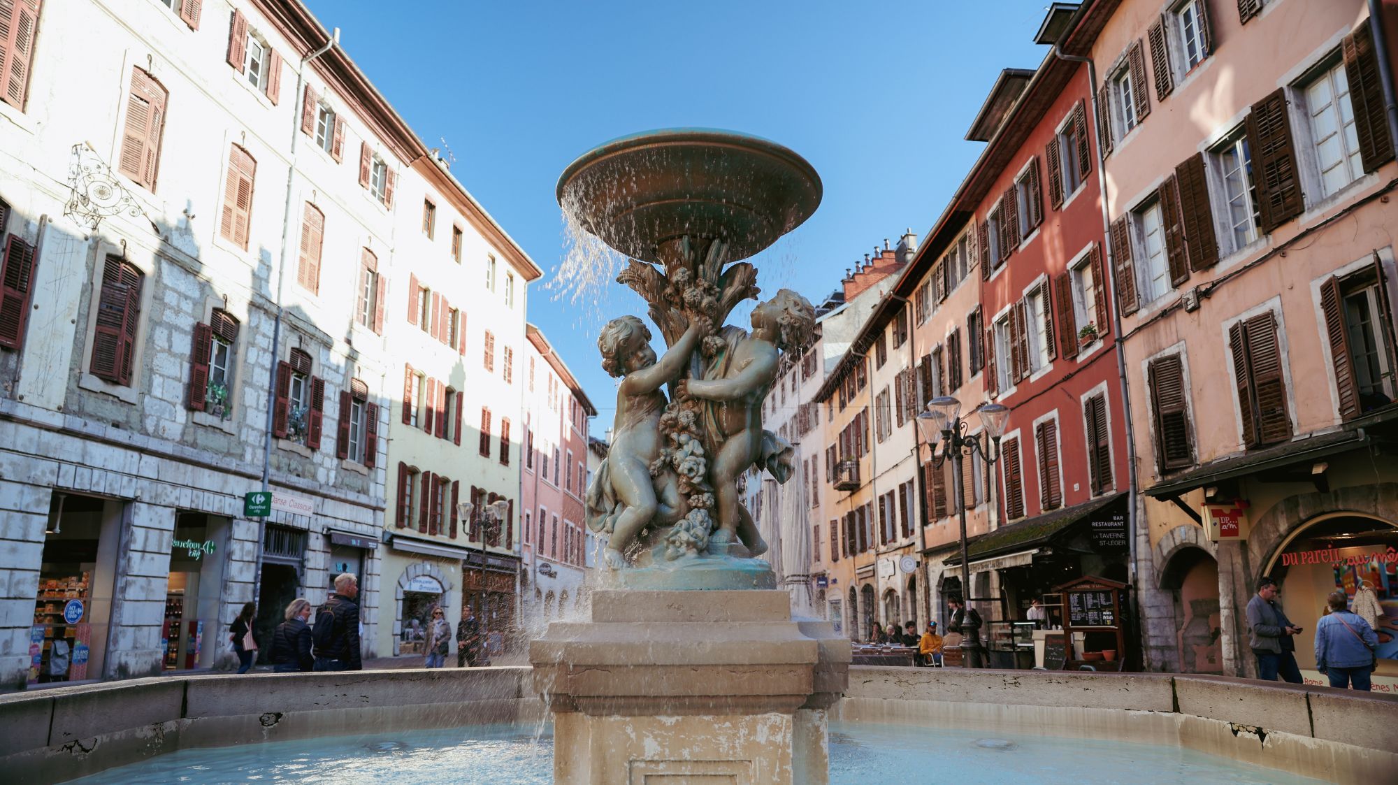 A fountain with bronze figures in a square of shuttered buildings in Chambéry