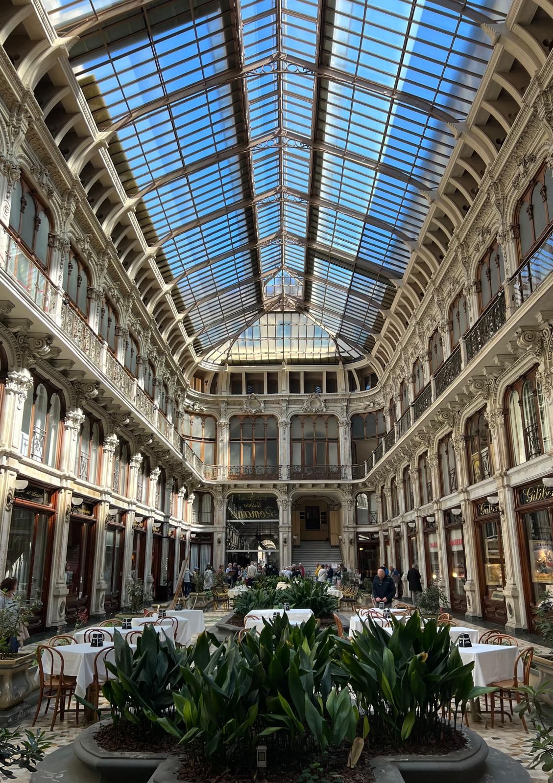 Café tables beneath the glass roof of a gallery in central Turin