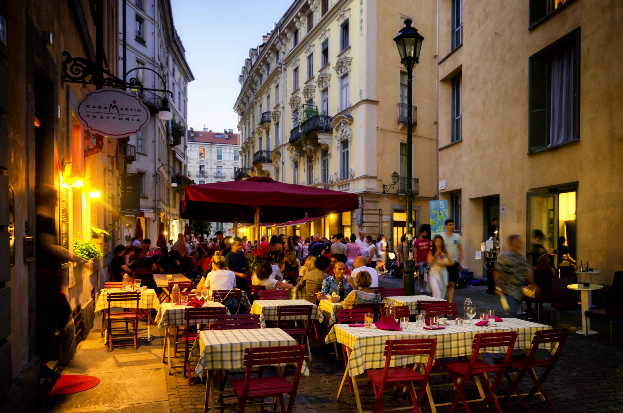 Evening tables outside a trattoria on a narrow street in Turin