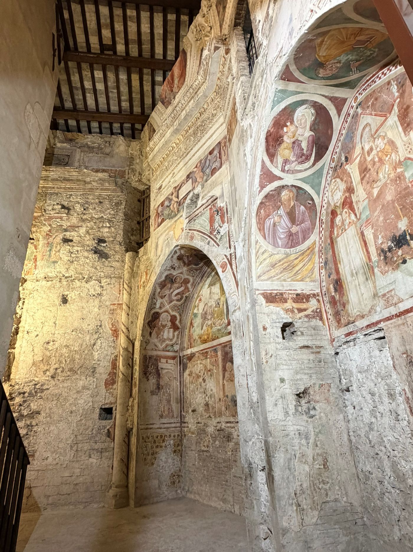 Weathered frescoes inside Spoleto Cathedral, with roundels of the Madonna and Child and a saint