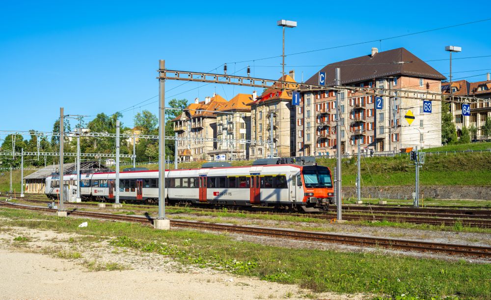 An SBB train at the platforms in La Chaux-de-Fonds, with hillside apartment buildings behind the tracks